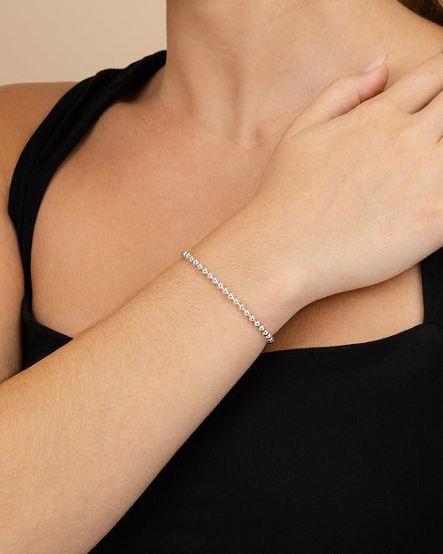 Silver bracelet on a person's wrist with a neutral background