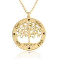 A gold family tree pendant necklace on a white background. The circular pendant features a cutout tree design with the names of family members engraved on the outer ring, including Luna, Andrew, Ezra, and Violet, accented by small black heart-shaped stones.