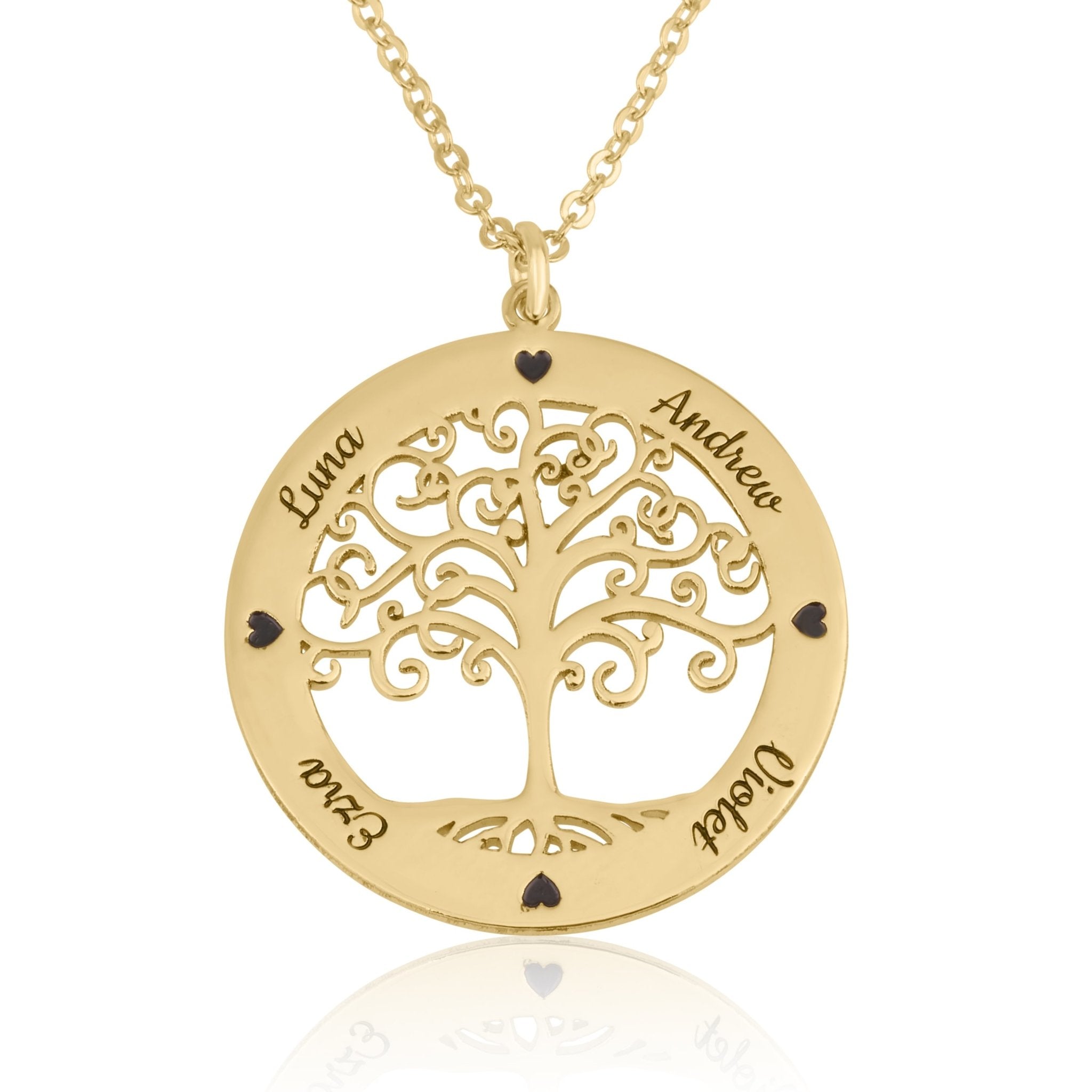 A gold family tree pendant necklace on a white background. The circular pendant features a cutout tree design with the names of family members engraved on the outer ring, including Luna, Andrew, Ezra, and Violet, accented by small black heart-shaped stones.